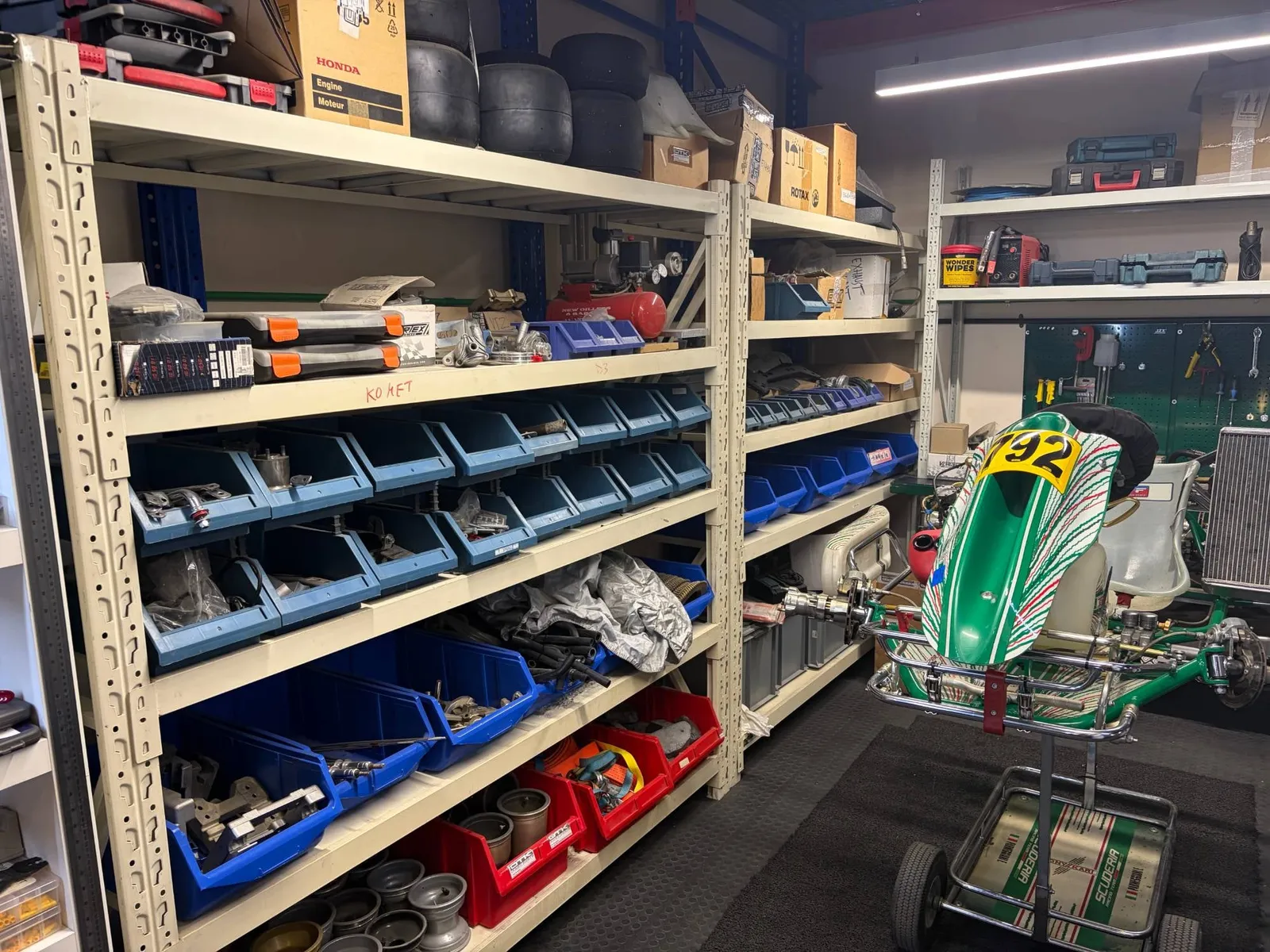Kart spare parts in labelled bins next to a Tony Kart